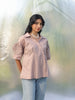 Woman in a brown shirt and light blue jeans standing amidst plastic wrap