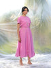 Woman wearing a pink top and skirt with floral details against a blurred natural background