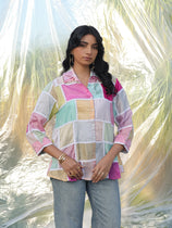 Woman wearing a colorful checkered shirt with a blurred natural background