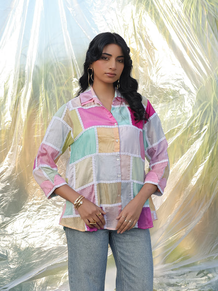 Woman wearing a colorful checkered shirt with a blurred natural background