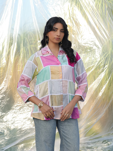 Woman wearing a colorful checkered shirt with a blurred natural background