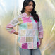 Woman wearing a colorful patchwork shirt with a light background