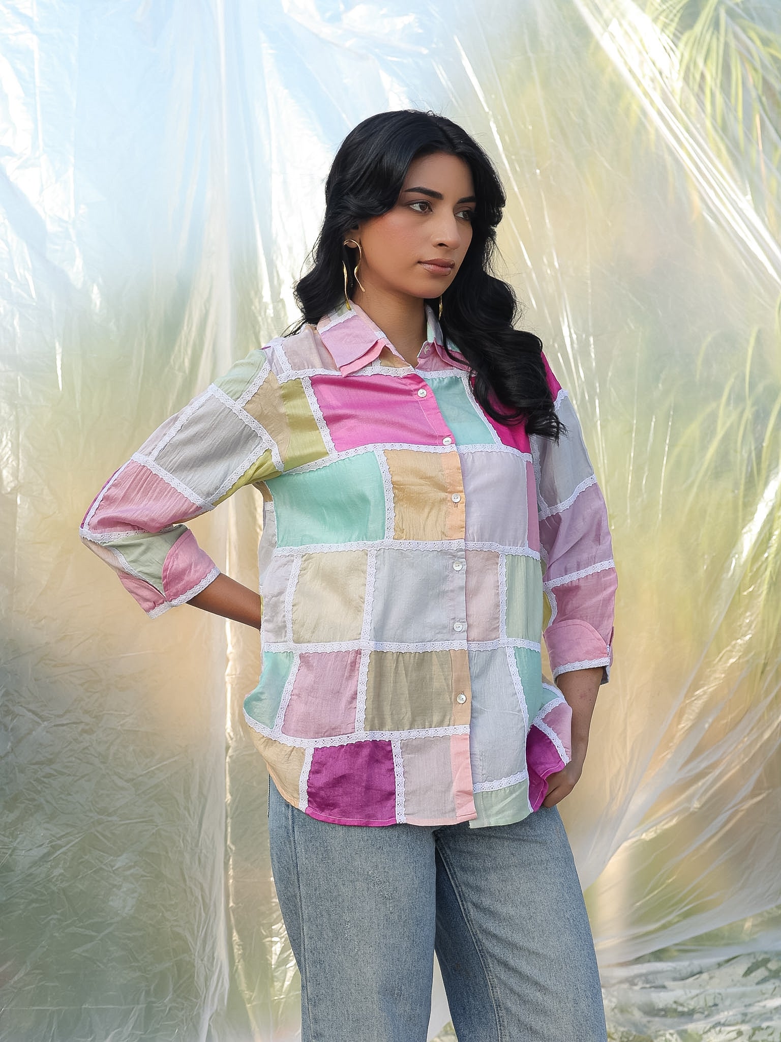 Woman wearing a colorful patchwork shirt with a light background