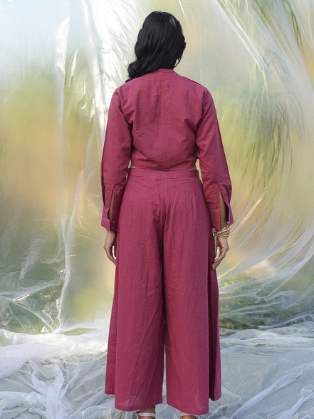 Person wearing a maroon coord set standing against a textured white background