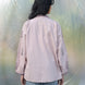 Person wearing a light pink embroidered shirt and blue jeans standing inside a large plastic bubble.