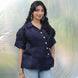 Woman wearing a dark blue blouse with ruffled sleeves against a light background