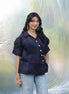 Woman wearing a dark blue blouse with ruffled sleeves against a light background