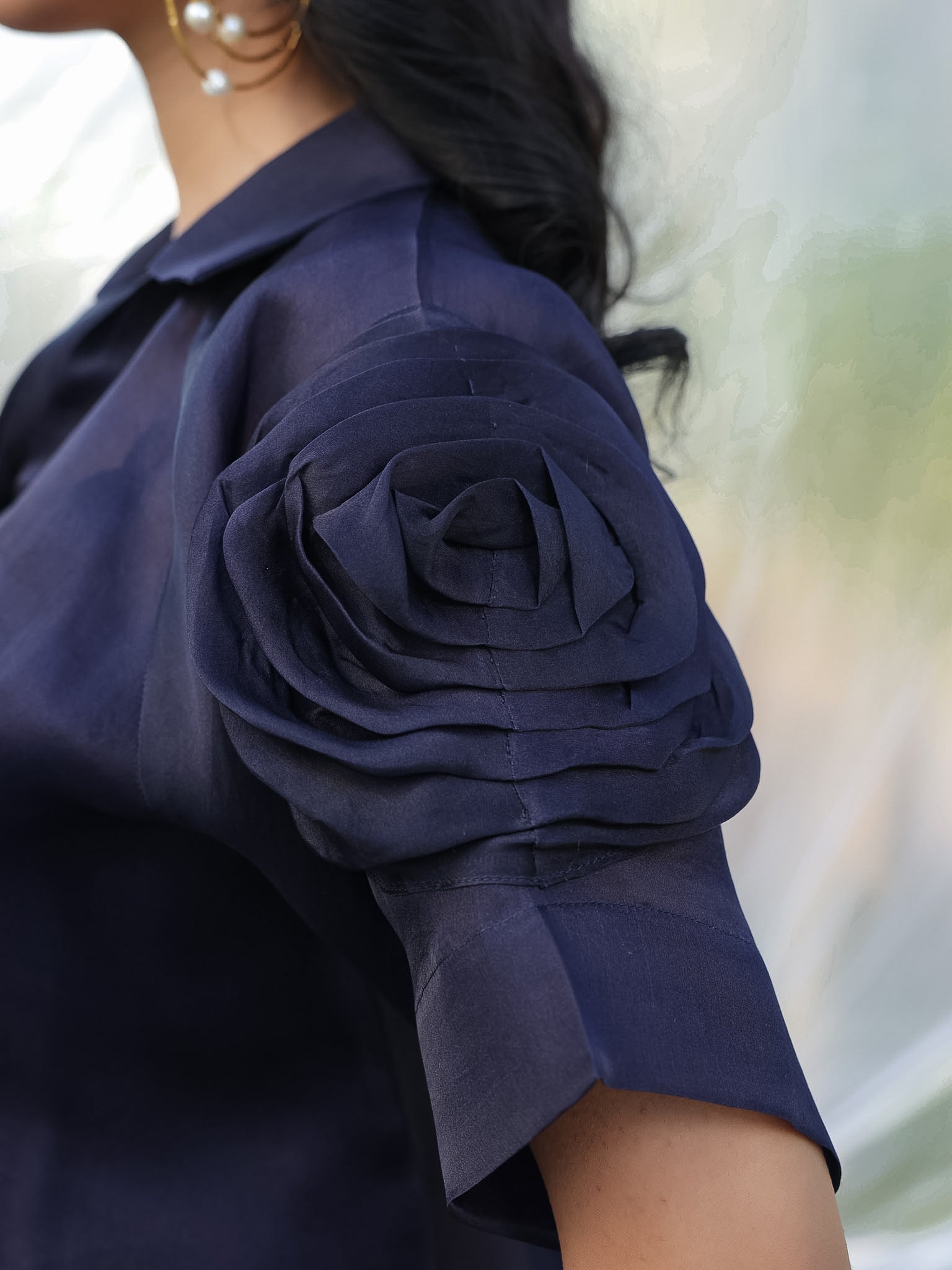 Navy blue shirt with a floral sleeve detail on a blurred background
