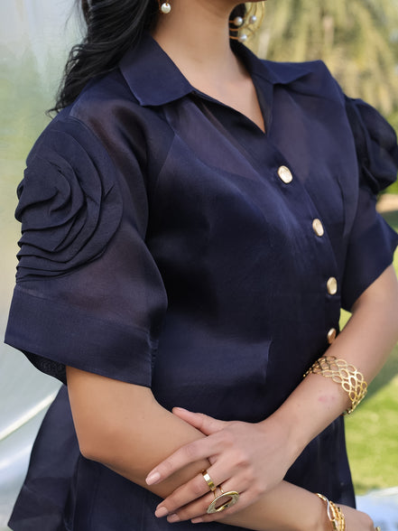Navy blue satin organza shirt with gold buttons worn by a person, blurred background