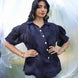 Woman wearing a navy blue shirt with ruffled sleeves against a white background