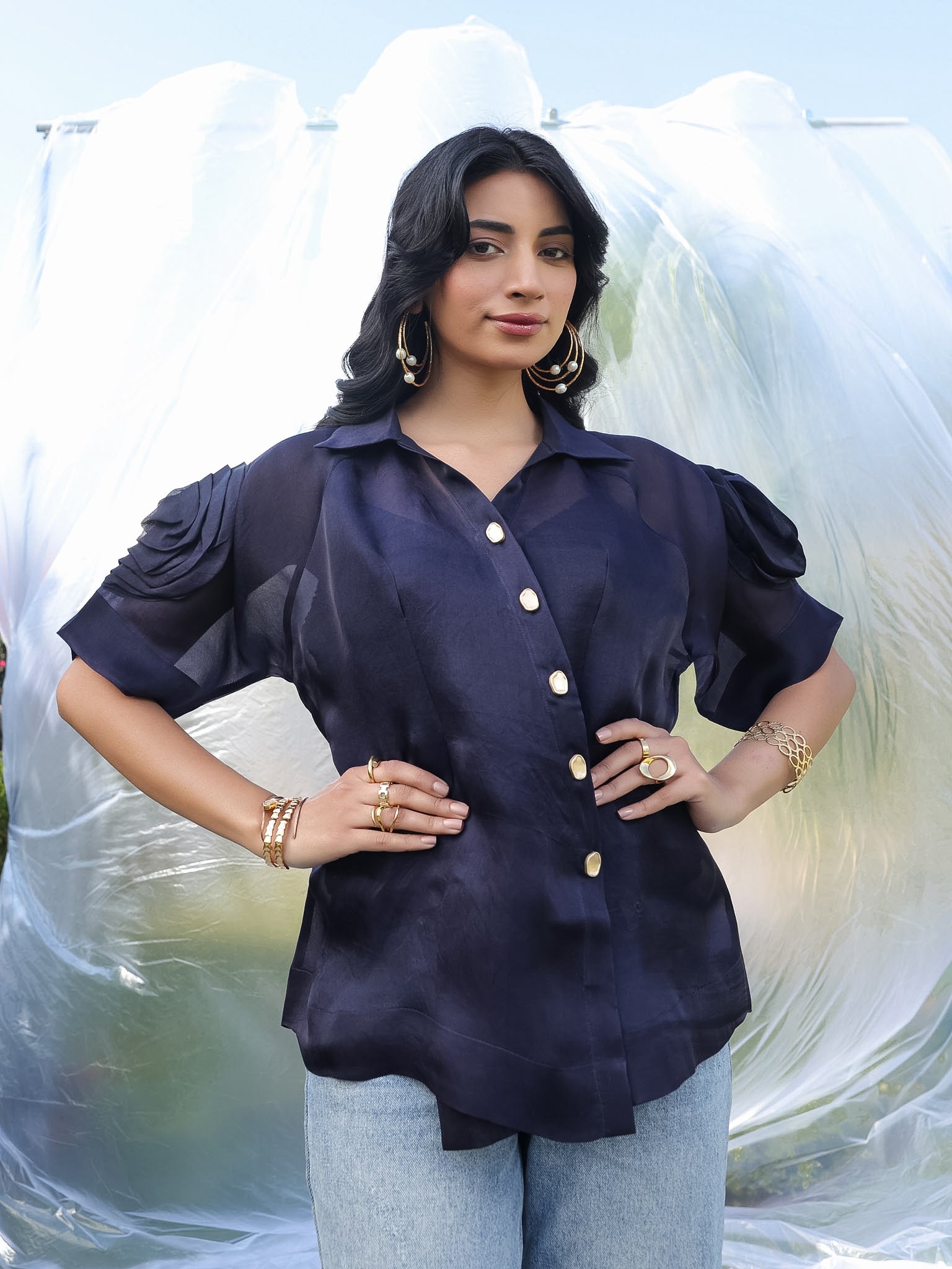 Woman wearing a navy blue shirt with ruffled sleeves against a white background