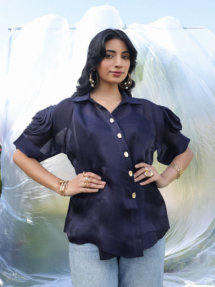 Woman wearing a navy blue shirt with ruffled sleeves against a white background