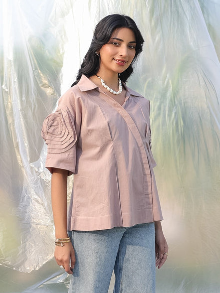 Woman wearing a party wear beige shirt and light blue jeans standing against a blurred natural background