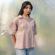 Woman in a brown shirt and light blue jeans standing amidst plastic wrap