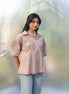 Woman in a brown shirt and light blue jeans standing amidst plastic wrap
