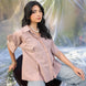 Woman in abrown shirt and jeans sitting on a chair with a blurred natural background