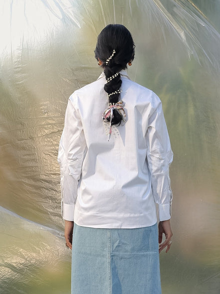 Person wearing a white shirt and light blue skirt standing in front of a large plastic sheet.