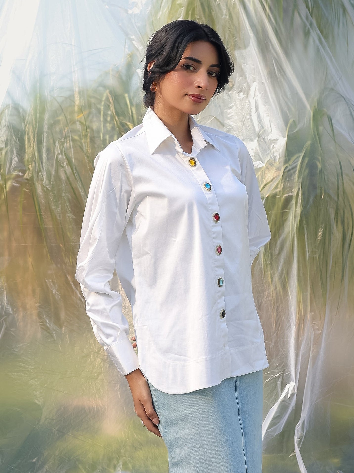 Woman wearing a white shirt with colorful stone buttons in a natural setting