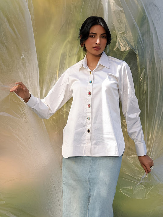 Woman wearing a white shirt and light blue skirt standing in front of a translucent curtain.
