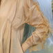 Beige shirt with ruffled sleeves against a blurred natural background