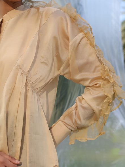 Beige shirt with ruffled sleeves against a blurred natural background