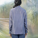 Person wearing a gray shirt and blue jeans standing in front of a plastic-wrapped landscape.