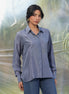 Woman wearing a grey shirt and jeans standing in front of a blurred natural background
