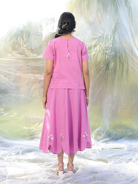 Person wearing a pink outfit with a blurred natural background