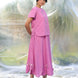 Woman wearing a pink top and skirt coord set with a blurred natural background