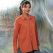 Woman wearing an orange shirt with a blurred natural background