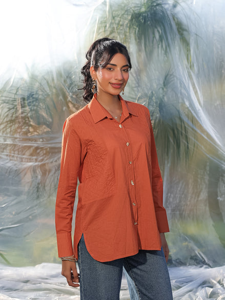 Woman wearing an orange shirt with a blurred natural background