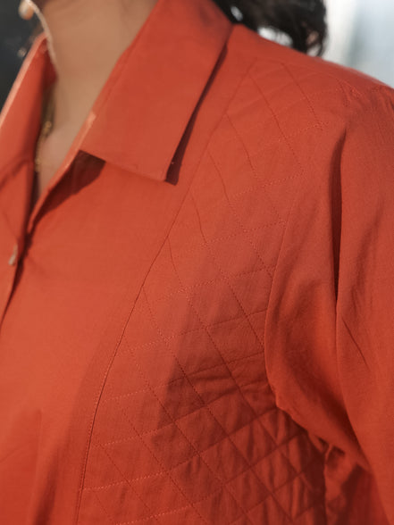 Close-up of a person wearing an orange quilted shirt