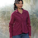 Woman wearing a maroon shirt and blue jeans standing on a textured surface