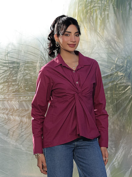 Woman wearing a maroon shirt and blue jeans standing on a textured surface