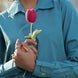 Person wearing a blue shirt holding a pink crocheted flower.