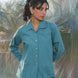 Woman wearing a teal shirt with stylish teal buttons with a blurred natural background