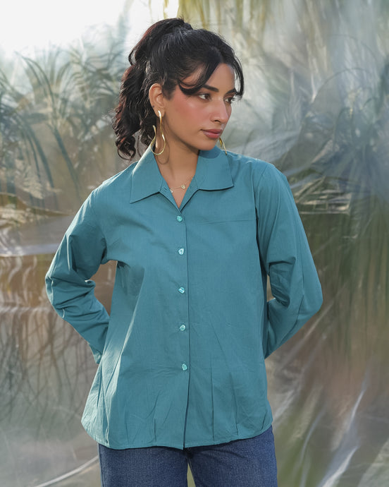 Woman wearing a teal shirt with stylish teal buttons with a blurred natural background
