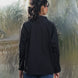Person wearing a black shirt and blue jeans standing in front of a plastic-wrapped landscape.