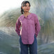 Woman wearing a pink stylish shirt and blue jeans standing against a textured white background