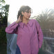 Woman wearing a purple shirt with cufflinks outdoors with a blurred background