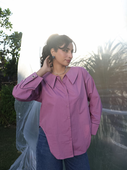 Woman wearing a purple shirt with cufflinks outdoors with a blurred background