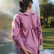 Person wearing a pink shirt with scallop yoke in back in an outdoor setting with plastic sheeting and trees in the background