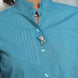 Close-up of a teal shirt with stylish collar, front pleats and classy buttons