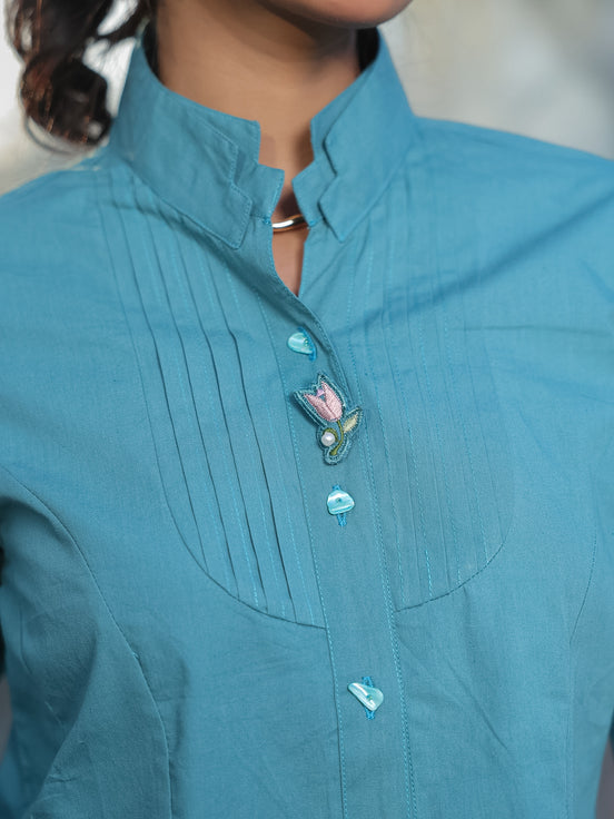 Close-up of a teal shirt with stylish collar, front pleats and classy buttons