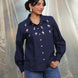 Woman wearing a navy blue embroidered shirt with a plain background
