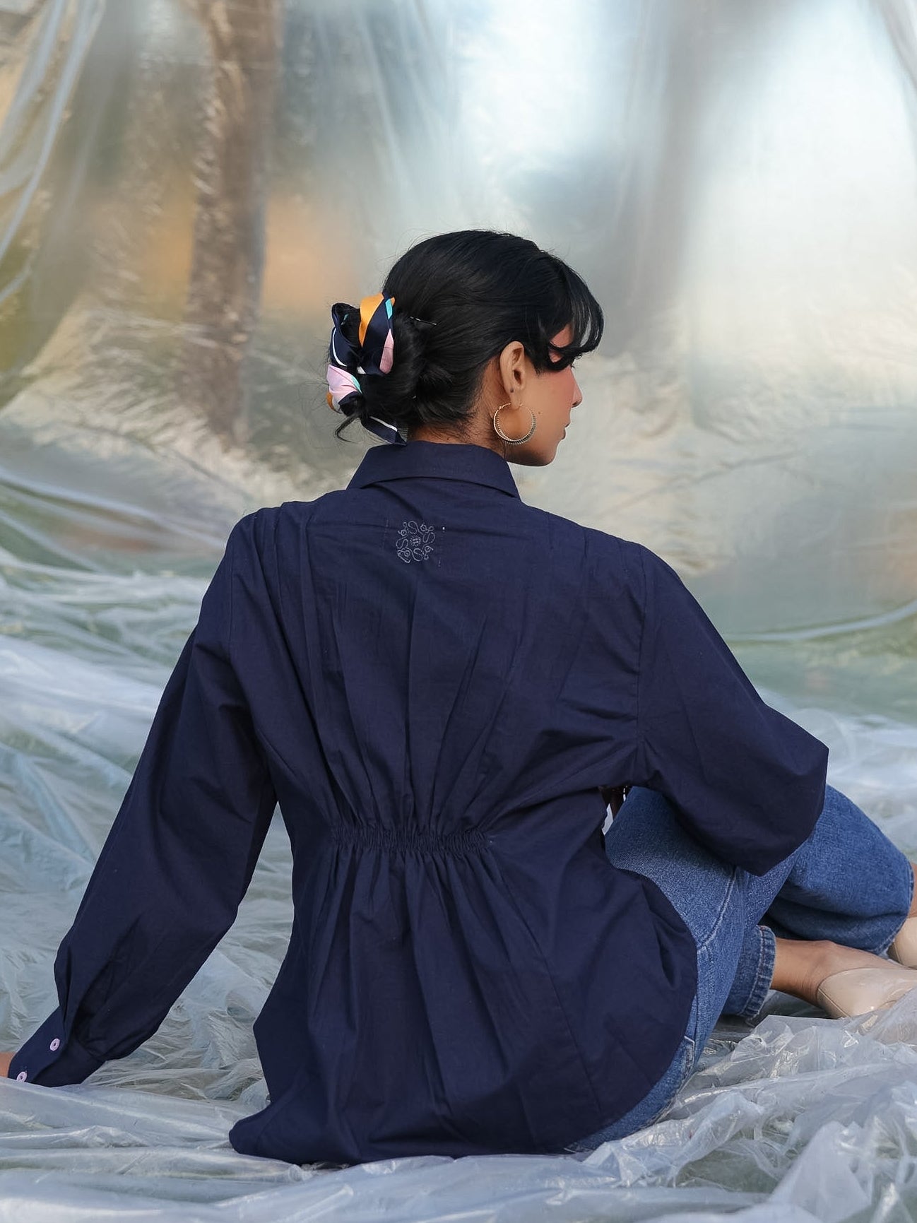 Person wearing a navy blue shirt sitting on a white surface with a reflective background