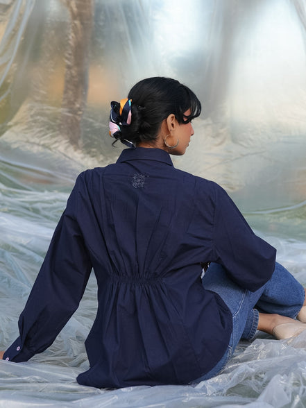 Person wearing a navy blue shirt sitting on a white surface with a reflective background
