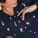 Woman wearing a navy blue shirt with pink floral embroidery