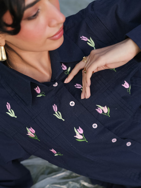 Woman wearing a navy blue shirt with pink floral embroidery