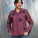 Woman wearing a purple shirt with dark blue tulip applique patches against a plain background